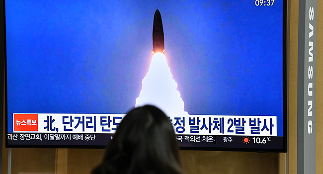 A woman watches a television news broadcast showing a file image of a North Korean missile test, at a railway station in Seoul on March 21, 2020. Jung Yeon-je / AFP