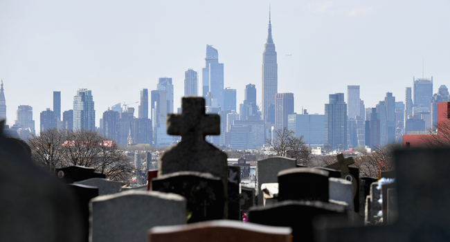 Gravestones from a cemetery are seen with the Manhattan skyline in the background on April 07, 2020 in Brooklyn, New York. Angela Weiss / AFP