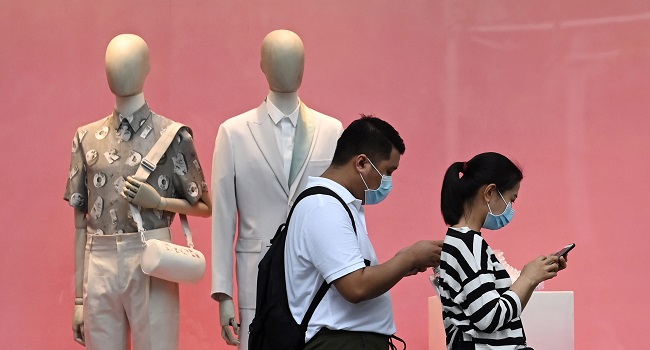 (FILES) In this file photo taken on June 18, 2020, a couple wearing face masks walk past a fashion retail outlet along the Orchard shopping belt in Singapore, a day ahead of further easing of restrictions in Singapore due to the COVID-19 novel coronavirus. - Singapore plunged into recession in the second quarter as growth fell 41.2 percent quarter-on-quarter with the trade-dependent economy hammered by the coronavirus, preliminary data showed on July 14. (Photo by Roslan RAHMAN / AFP)