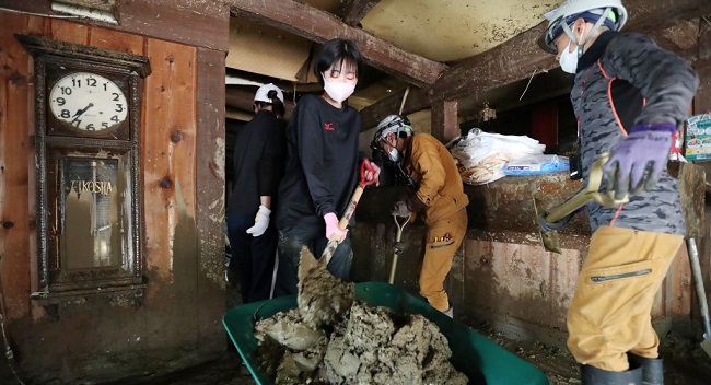 High school students shovel off the mud from a ryokan, a traditional Japanese style hotel, in the aftermath of heavy flooding in Hitoyoshi, Kumamoto prefecture on July 9, 2020. - Japanese emergency services and troops scrambled on July 9 to reach thousands of homes cut off by catastrophic flooding and landslides that have killed dozens and caused widespread damage. (Photo by STR / JIJI PRESS / AFP) / Japan OUT