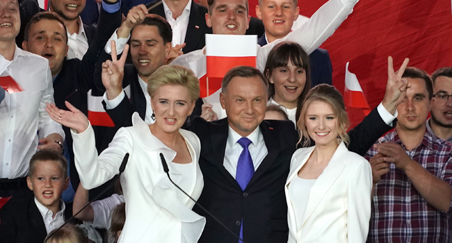 Polish President Andrzej Duda flashes V-signs after addressing supporters with his wife Agata as exit poll results were announced during the presidential election in Pultusk, Poland, on July 12, 2020 . JANEK SKARZYNSKI / AFP