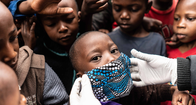 A boy tries to wear a face mask as members of Coalition for grassroots human rights defenders Kenya (CGHRD'S Kenya) work for their food distribution, a bag contains 2kg of maize flour, 1kg each of sugar and rice, soap, tea, salt and a face mask, to vulnerable families that have lost their income in the menace of the COVID 19 coronavirus in Mathare slum, Nairobi, on April 25, 2020. Fredrik Lerneryd / AFP