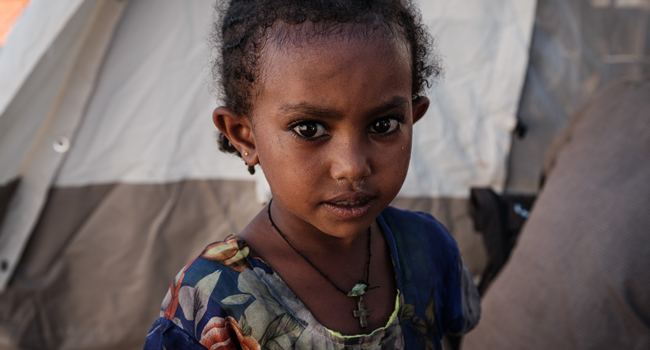 A 4-year-old Ethiopian refugee girl poses for a photograph at the Village Eight transit centre which hosts Ethiopian refugees who fled the Ethiopia's Tigray conflict near the Ethiopian border in Gedaref, eastern Sudan, on December 2, 2020. Yasuyoshi CHIBA / AFP