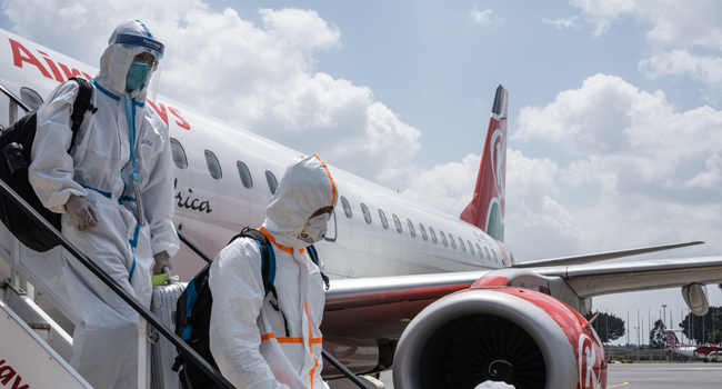 Passengers wearing full personal protective gears get off a plane at Jomo Kenyatta International Airport in Nairobi, Kenya, on January 19, 2021.  Yasuyoshi CHIBA / AFP