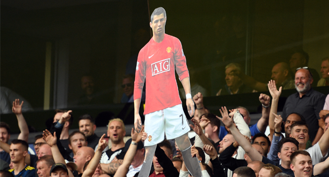 A cardboard cut out of new signing Cristiano Ronaldo is held by Manchester United supporters during the English Premier League football match between Wolverhampton Wanderers and Manchester United at the Molineux stadium in Wolverhampton, central England on August 29, 2021. Oli SCARFF / AFP