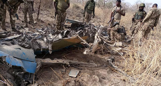 This photo, released by the Nigerian Army on March 26, 2022, shows troops standing beside what the army says are ruins of crashed Alpha Jet aircraft (NAF475).