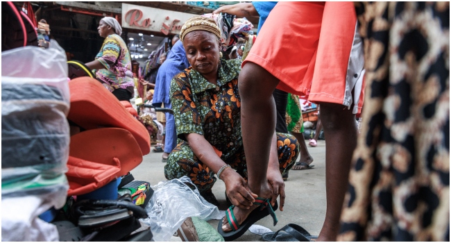 Shoe seller Bidemi Bello attends a costumer while selling sandals at her stall in the Balogun Market in Lagos on December 18, 2023. Christmas and year-end celebrations are marred by the economic crisis and soaring prices in Nigeria.