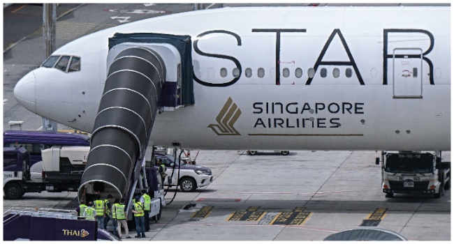 Officials enter the Singapore Airlines Boeing 777-300ER airplane, which was headed to Singapore from London before making an emergency landing in Bangkok due to severe turbulence, as it is parked on the tarmac at Suvarnabhumi International Airport in Bangkok on May 22, 2024. (Photo by Lillian SUWANRUMPHA / AFP)